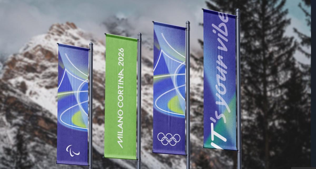A photo of four blue and green flags in front of a mountain.